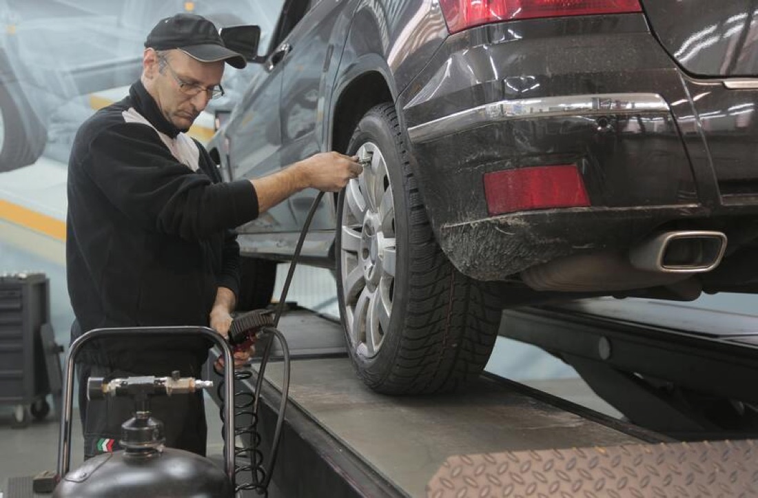 A technician servicing a wheel on a lifted vehicle.