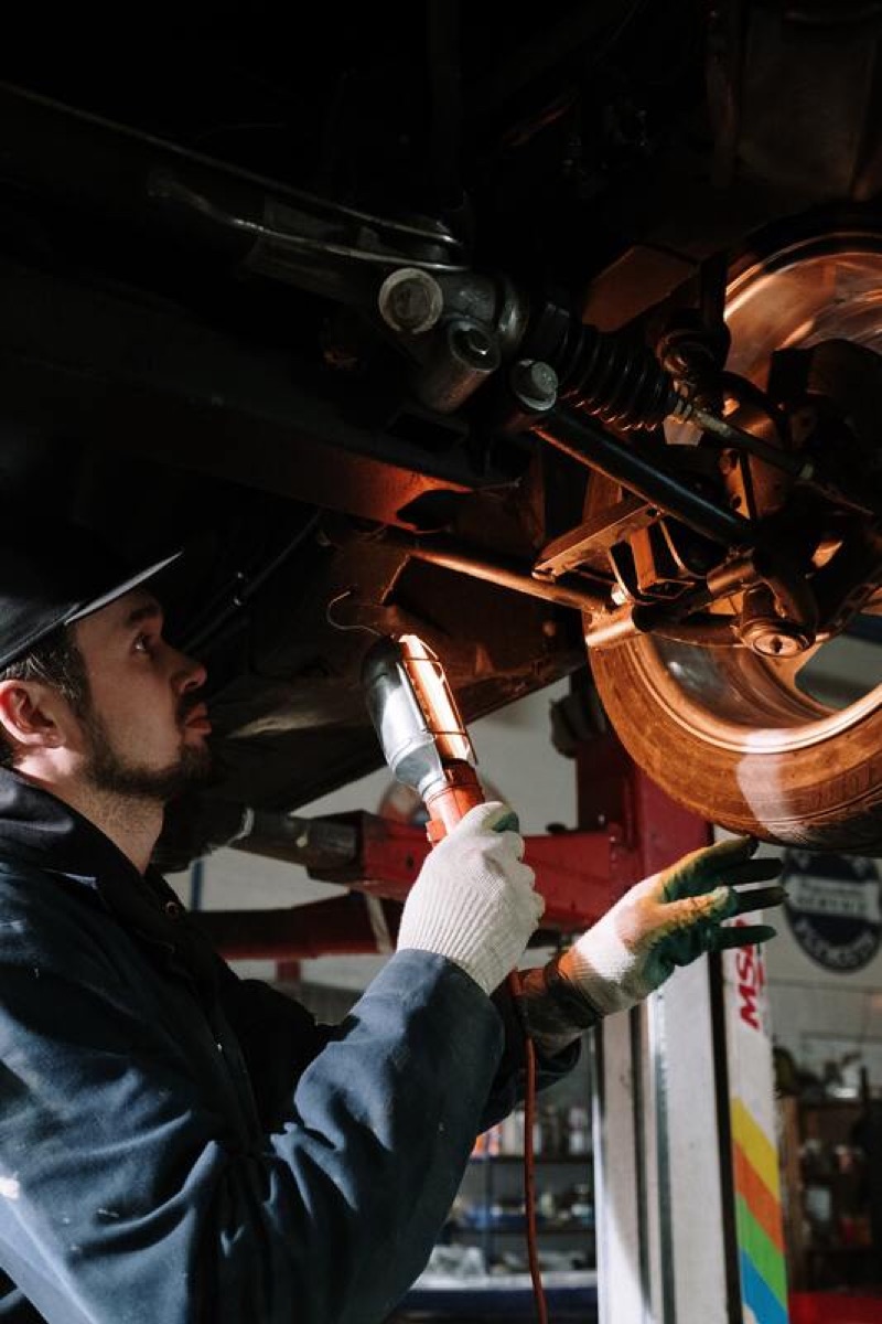A technician working underneath a car on the lift.